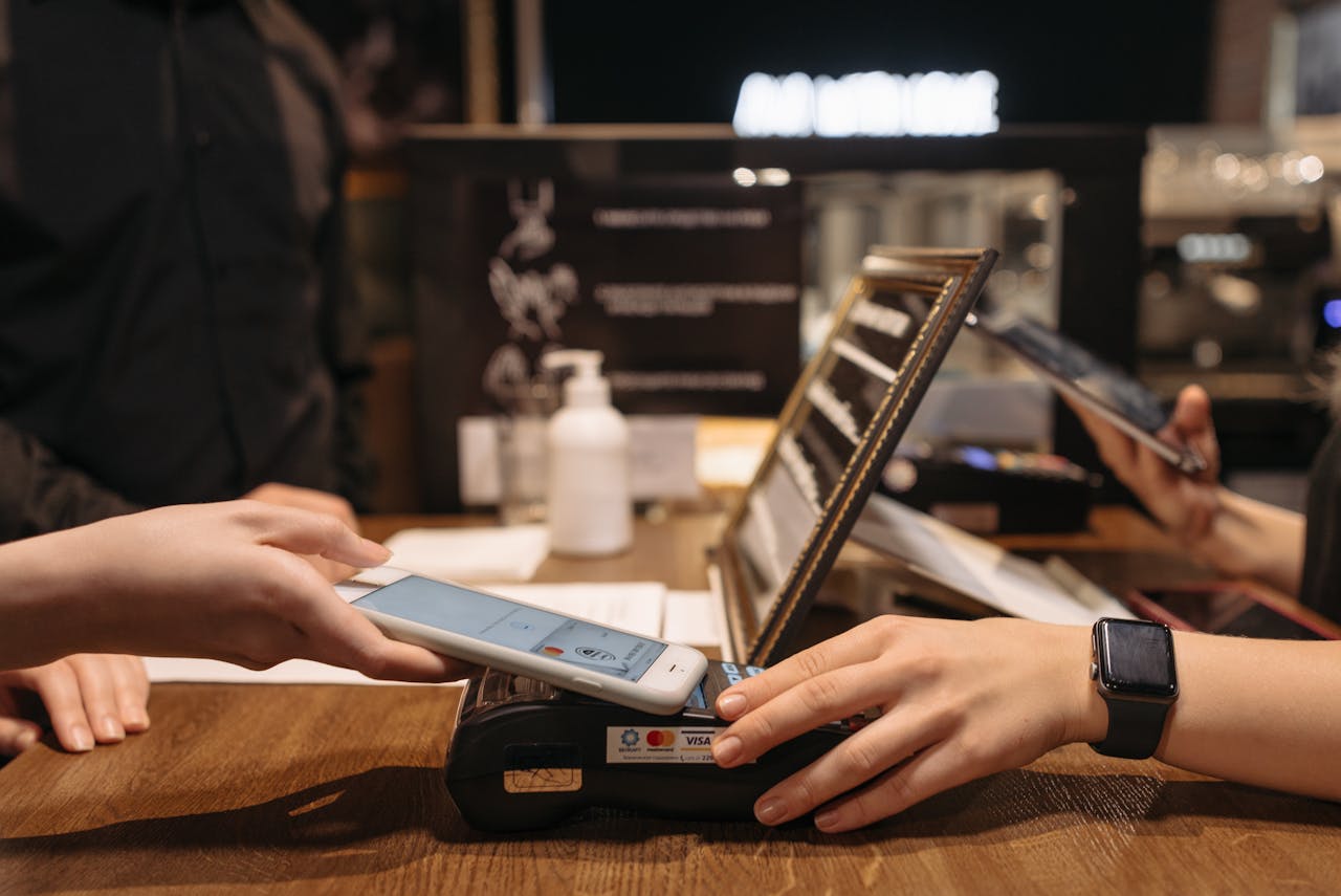 Services-02 Hands using mobile for contactless payment at café terminal.
