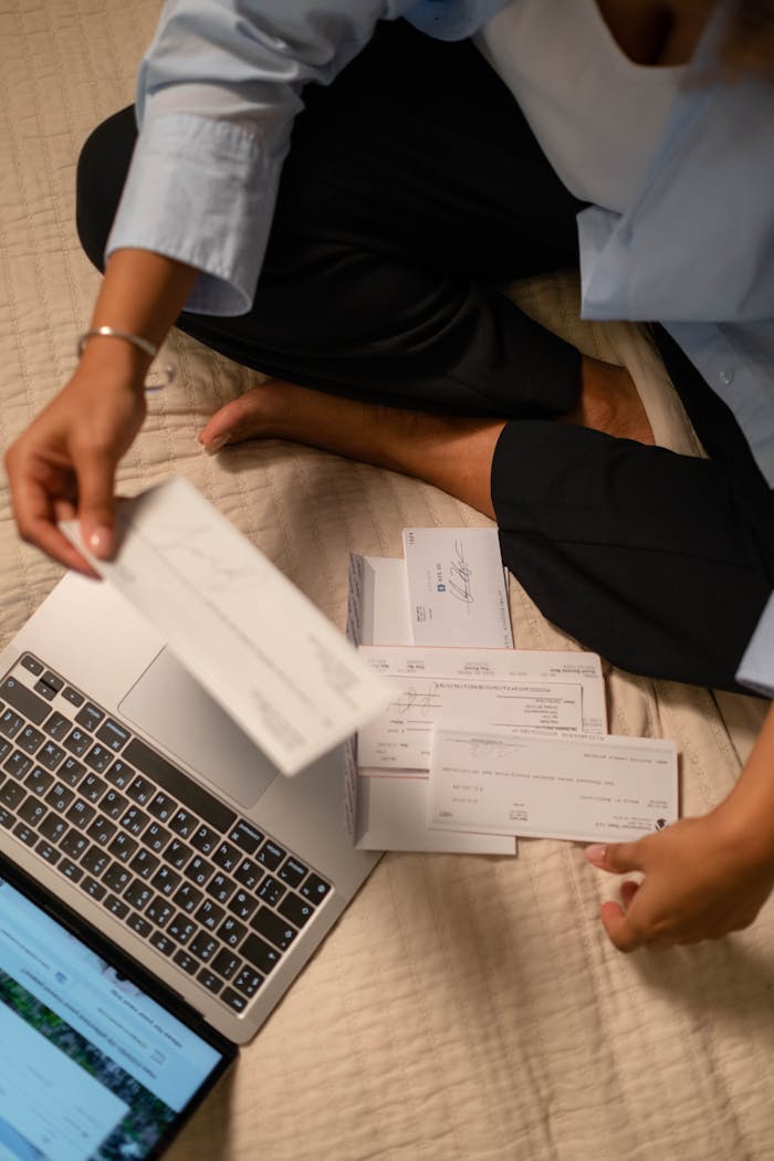 why-choose-us An adult organizing cheques and using a laptop indoors for financial tasks.